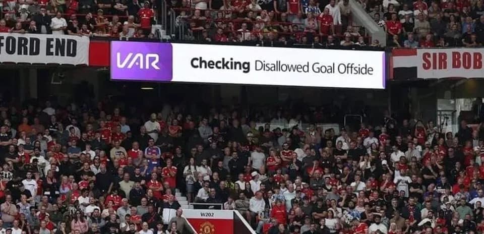 Фанаты на стадионе смотрят VAR на экране