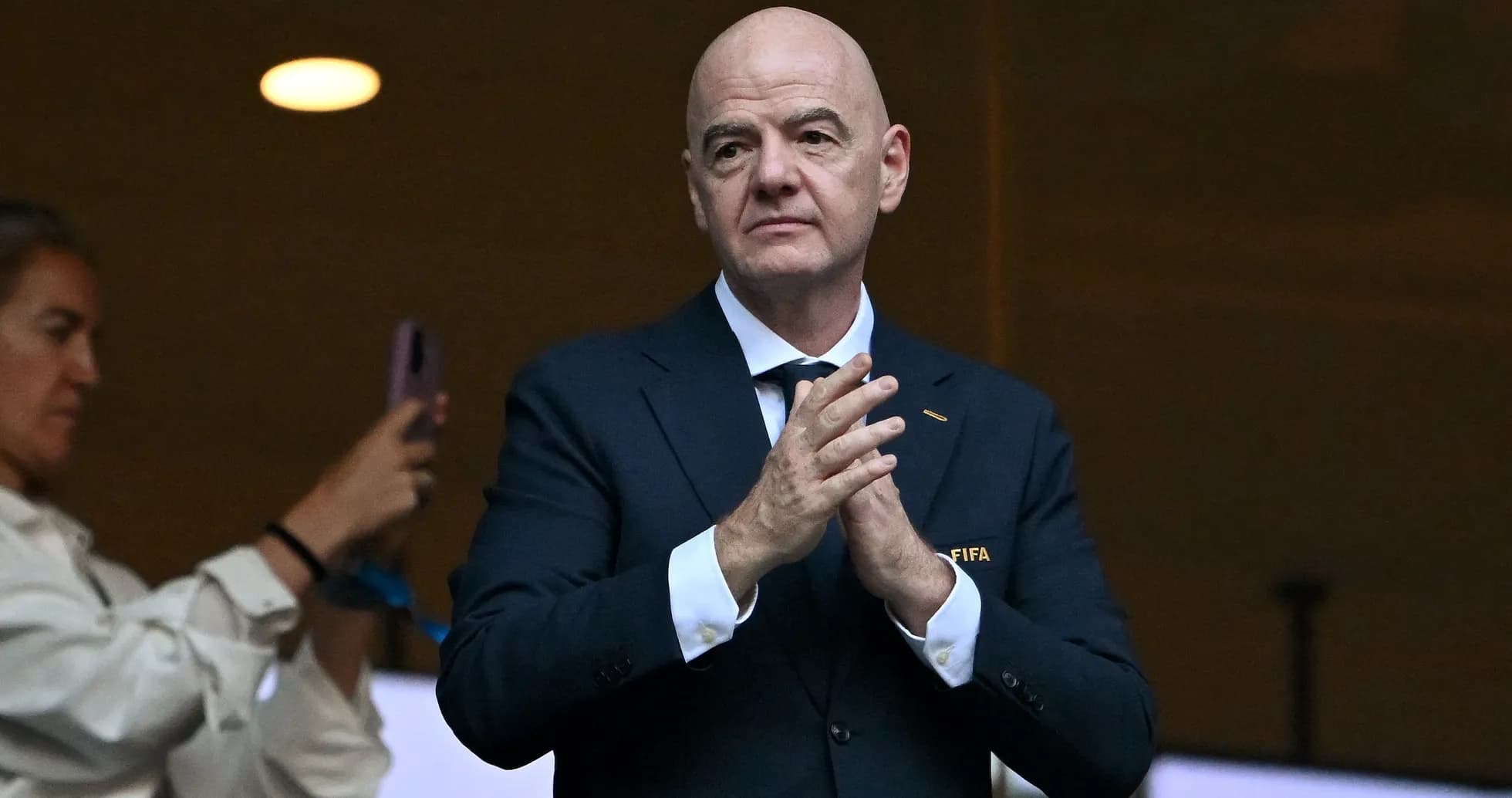Человек в костюме с логотипом FIFA аплодирует