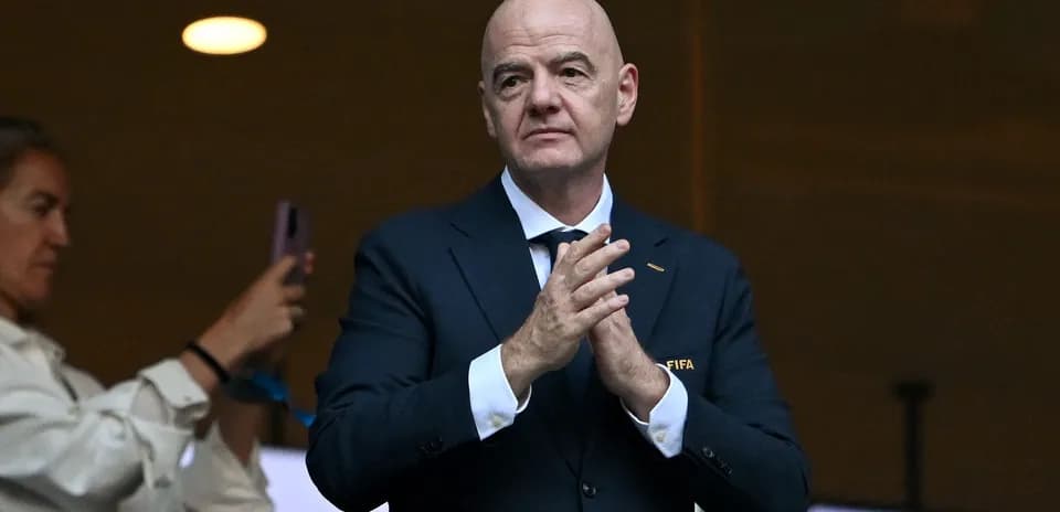 Человек в костюме с логотипом FIFA аплодирует