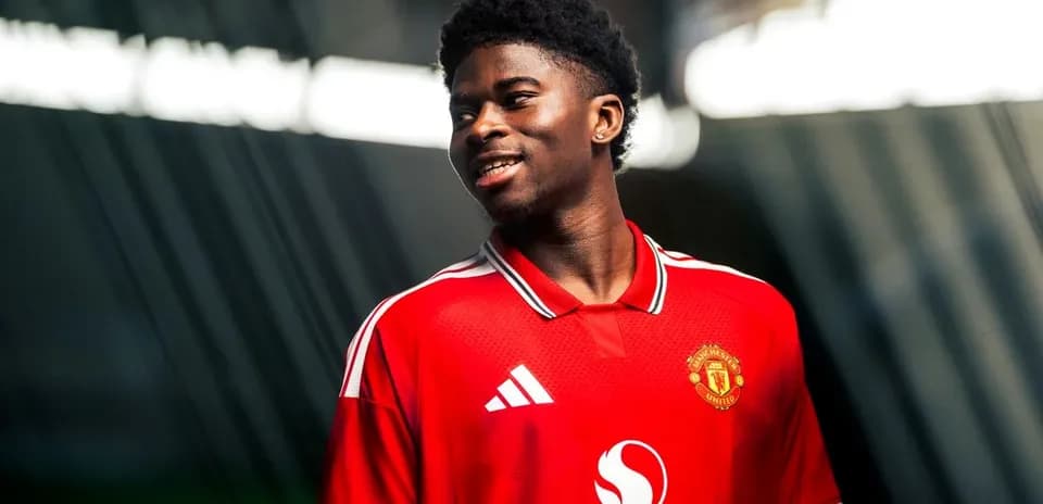 Игрок в красной футболке Manchester United улыбается