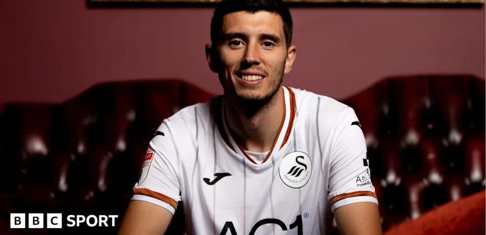 Игрок в футболке Swansea City сидит на диване