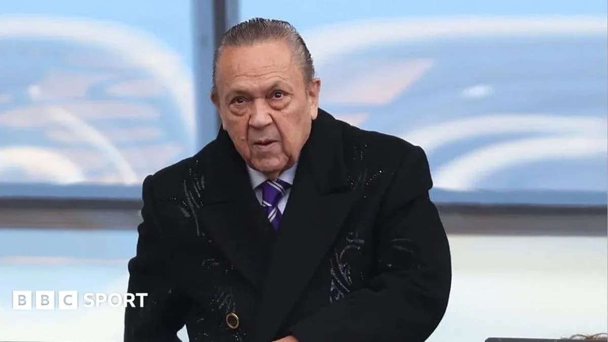 Человек в черном пальто на трибуне стадиона