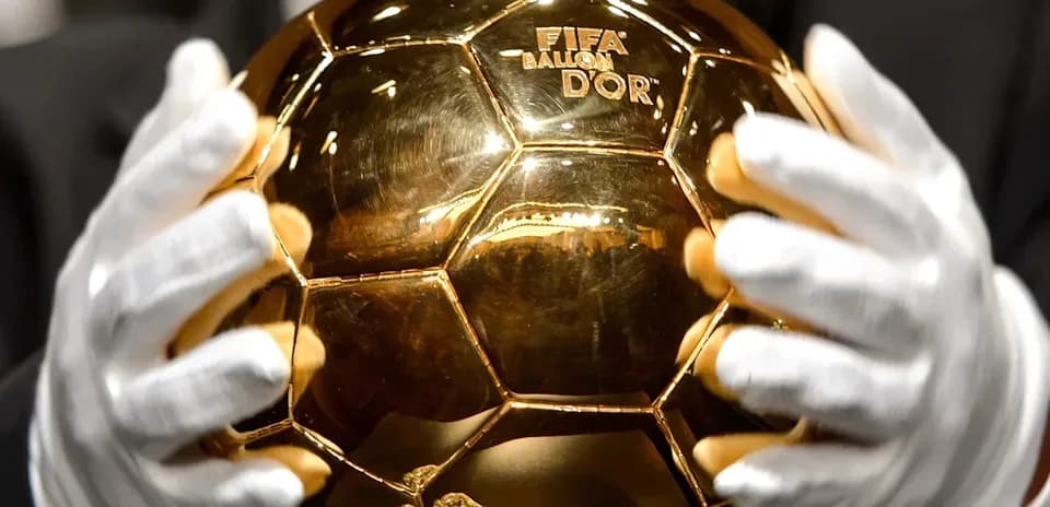 Человек держит Золотой мяч FIFA в перчатках