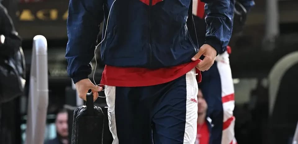 Игрок в спортивной одежде идет к автобусу