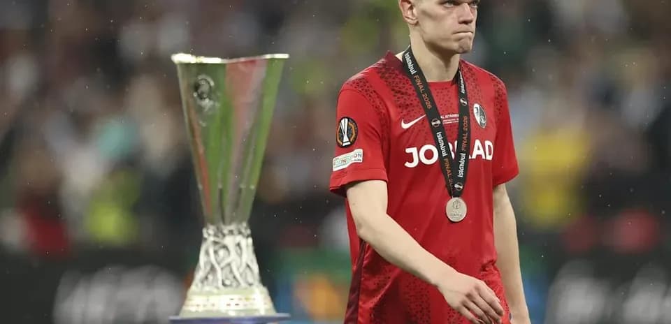 Игрок в красной форме с медалью рядом с кубком