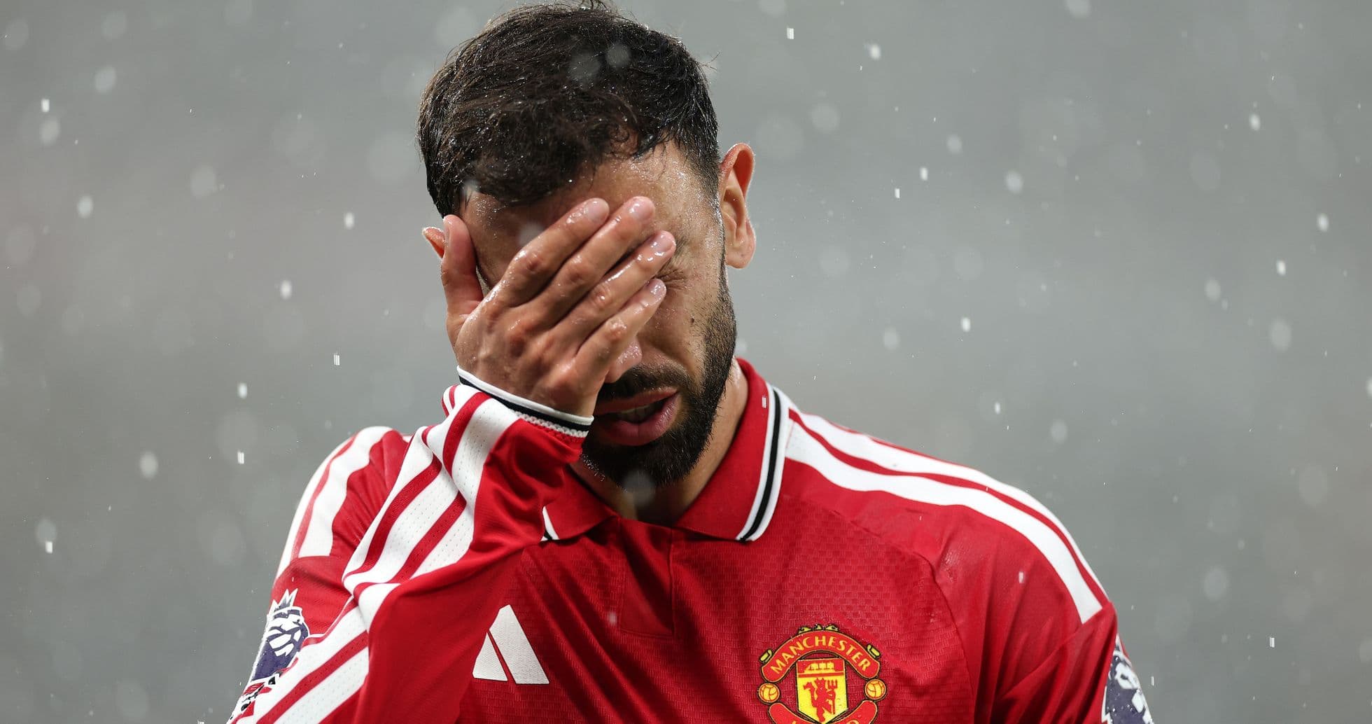 Игрок Manchester United прикрывает лицо рукой в дождь Игрок Manchester United прикрывает лицо рукой в дождь