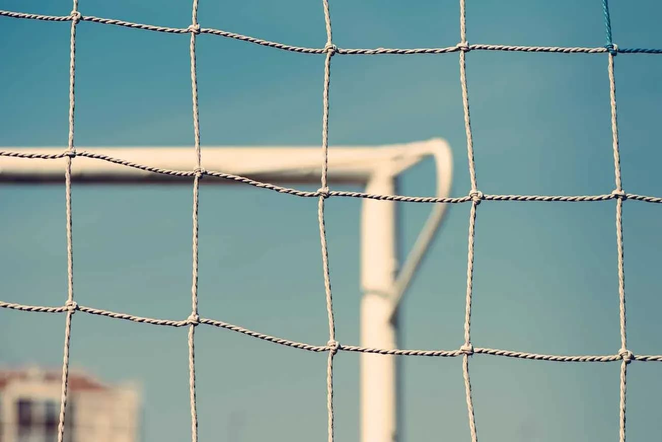 Сетчатая ворота футбольного поля на фоне неба Сетчатая ворота футбольного поля на фоне неба