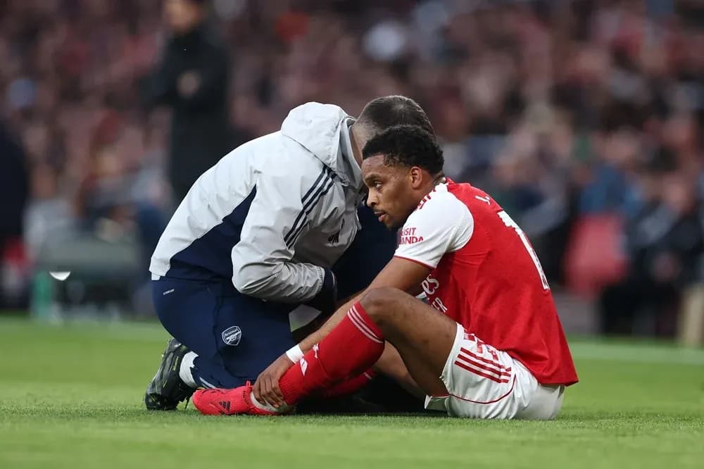 Игрок Arsenal сидит на поле с медицинским работником Игрок Arsenal сидит на поле с медицинским работником
