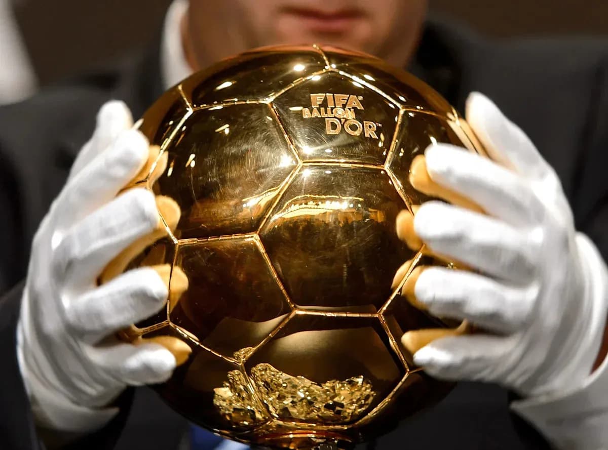 Человек держит Золотой мяч FIFA в перчатках Человек держит Золотой мяч FIFA в перчатках