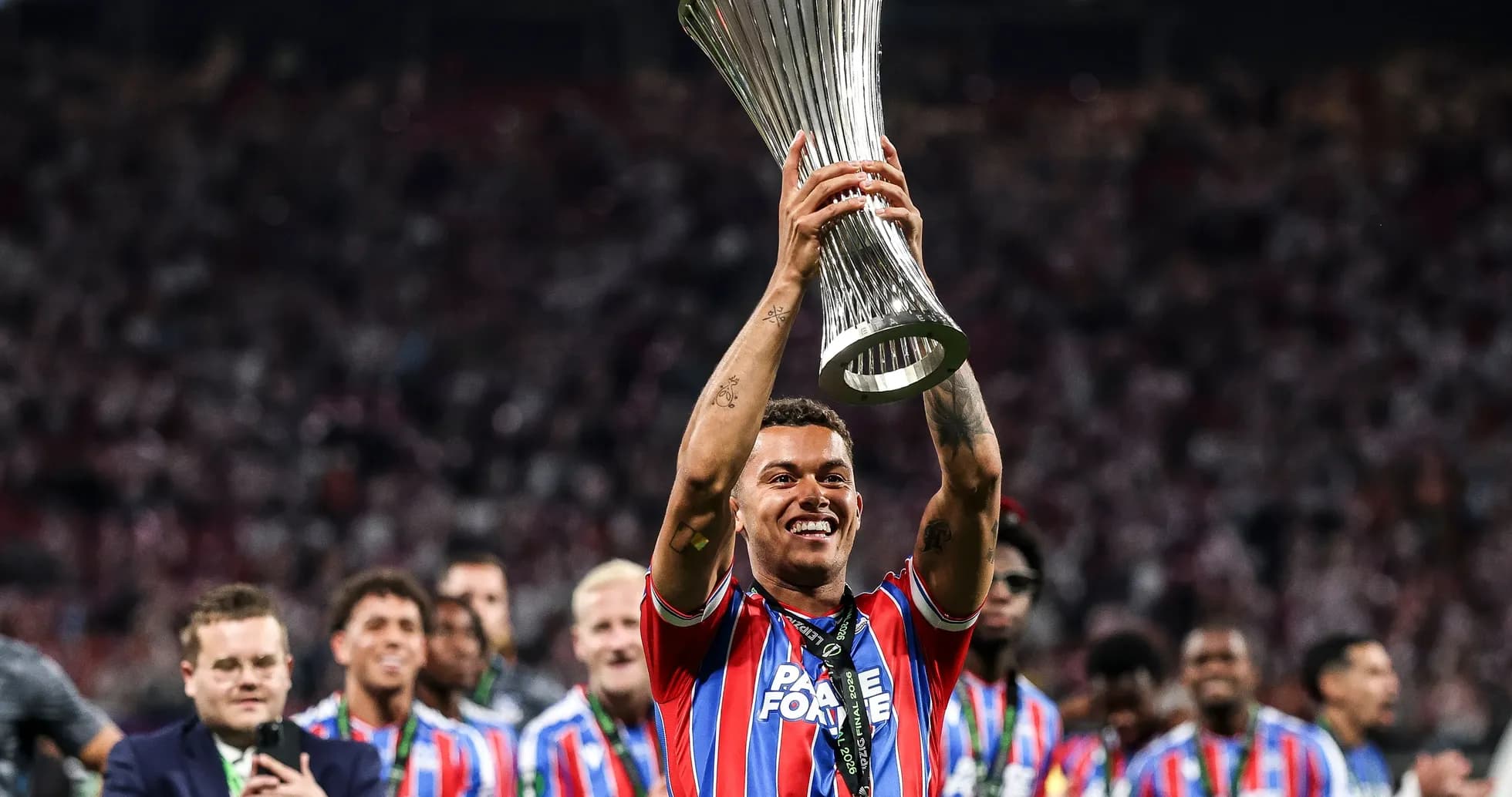 Игрок поднимает трофей UEFA на стадионе Игрок поднимает трофей UEFA на стадионе