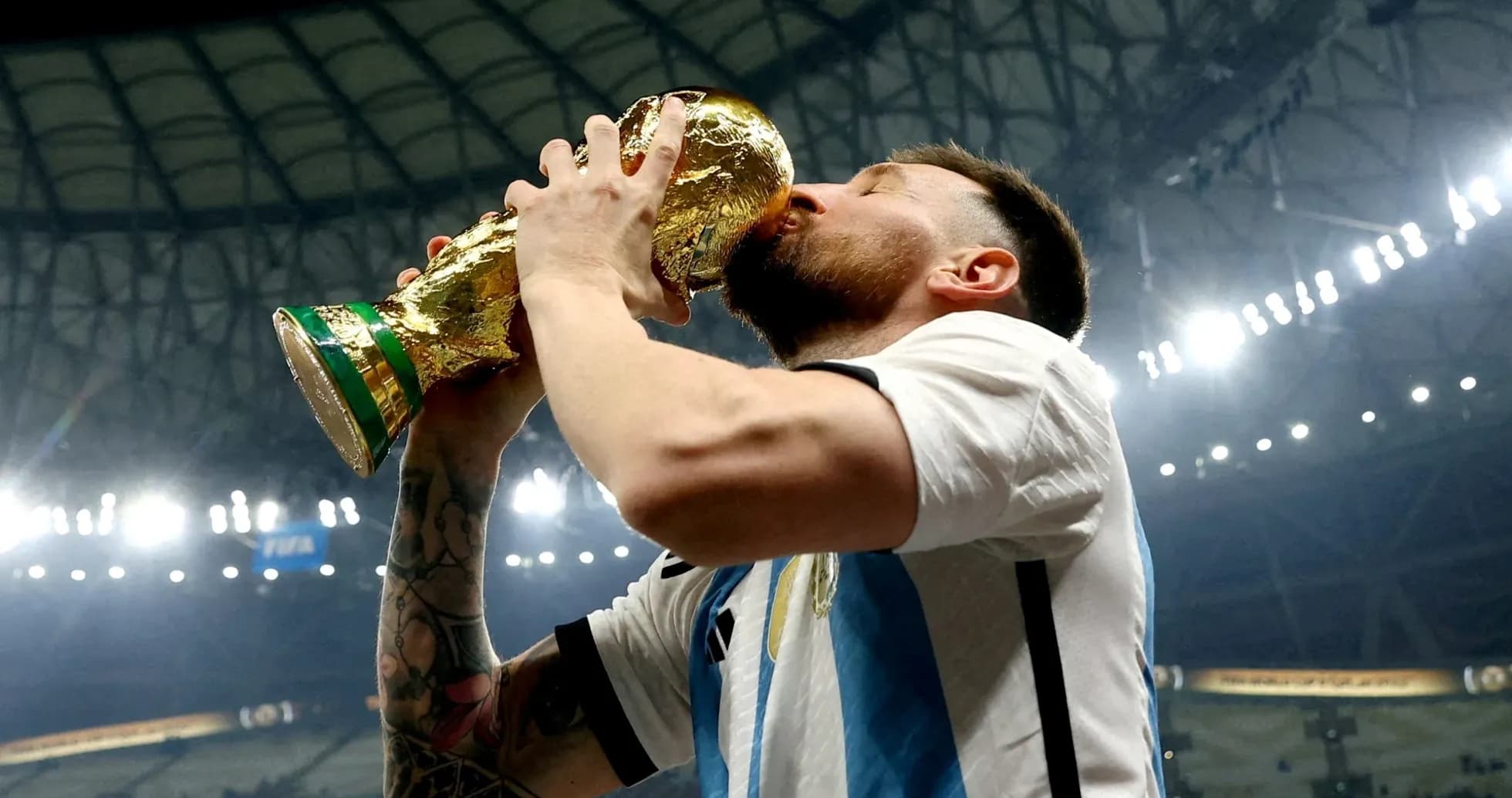 Игрок целует кубок чемпионата мира на стадионе Игрок целует кубок чемпионата мира на стадионе